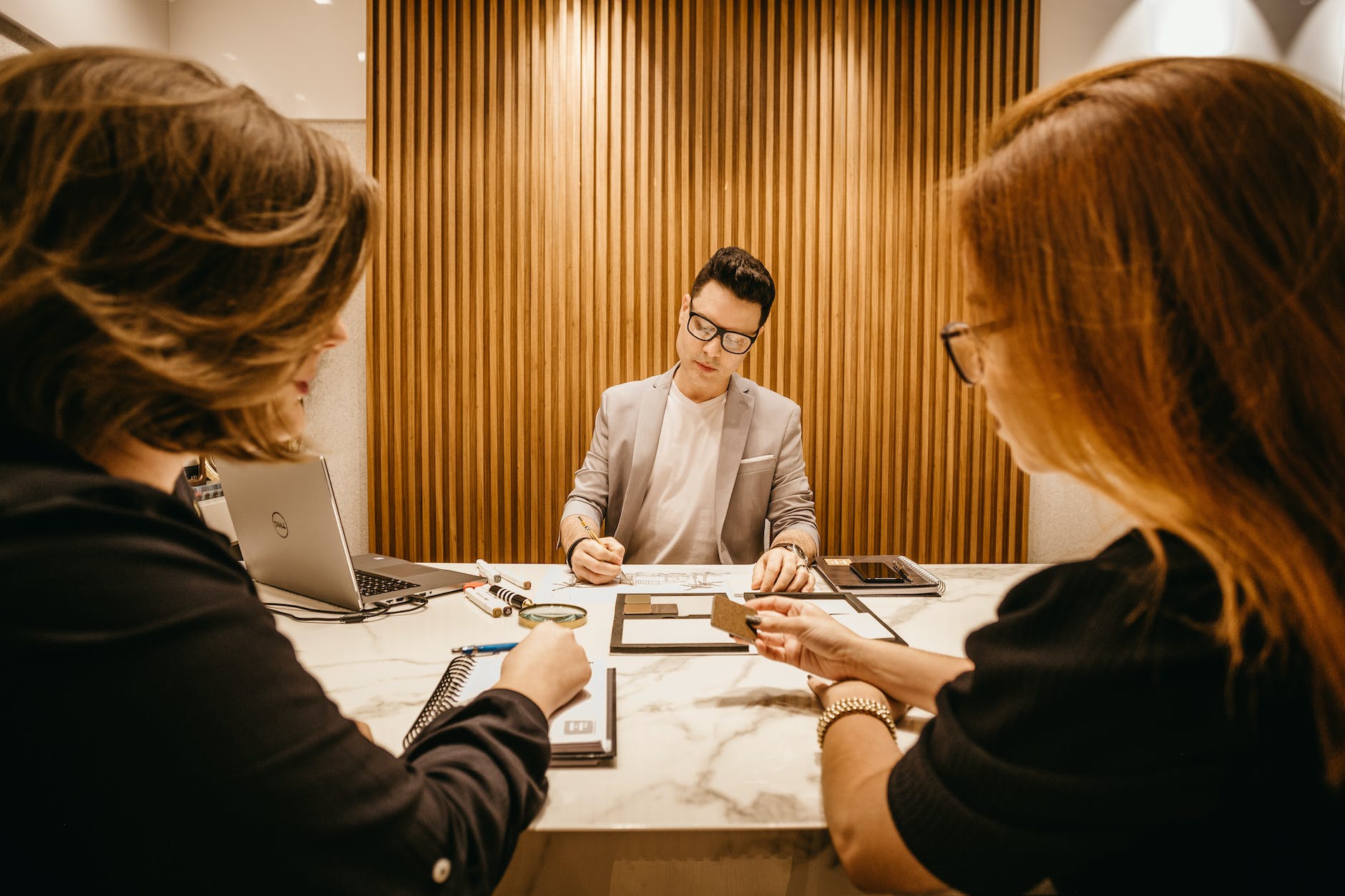 two women sitting beside desk near man