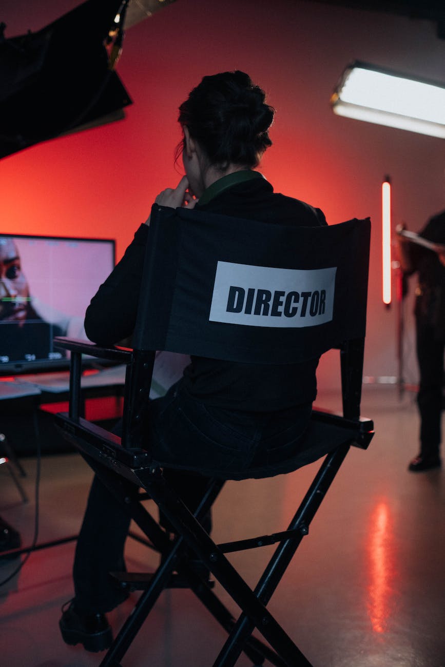 a person sitting on directors chair near a tv screen